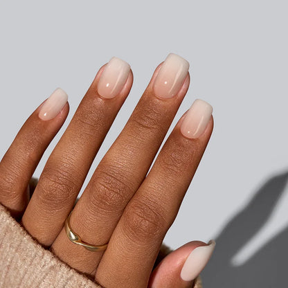 Hand with beige nail polish on a neutral background