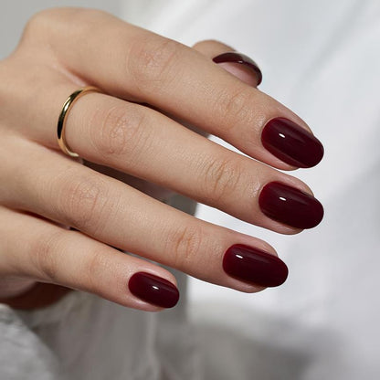Hand with dark red nail polish on a neutral background