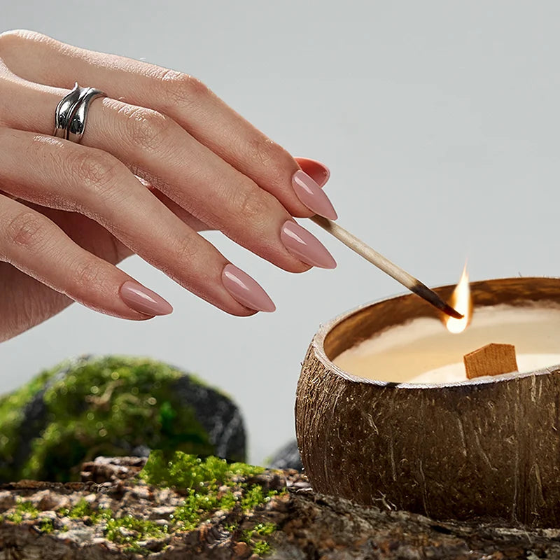 Hand lighting a coconut shell candle with a natural background