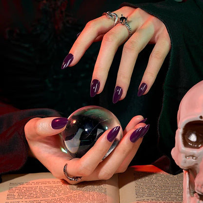 Close-up of hands with purple nail polish holding a crystal ball over an open book.