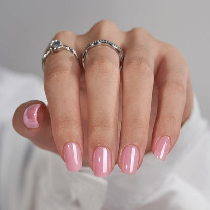 Hand with pink nail polish and silver rings on a neutral background