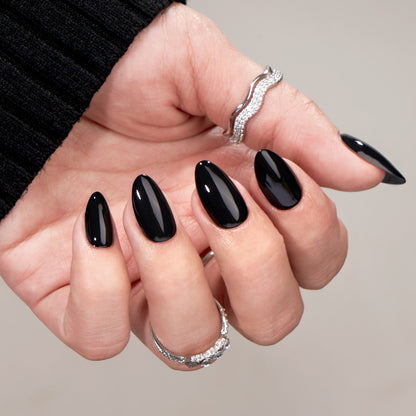 Hand with black nail polish and silver rings on a neutral background